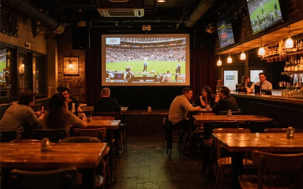 加拿大本地酒吧或餐厅内升级后的观赛区，温暖灯光与大屏幕，顾客期待